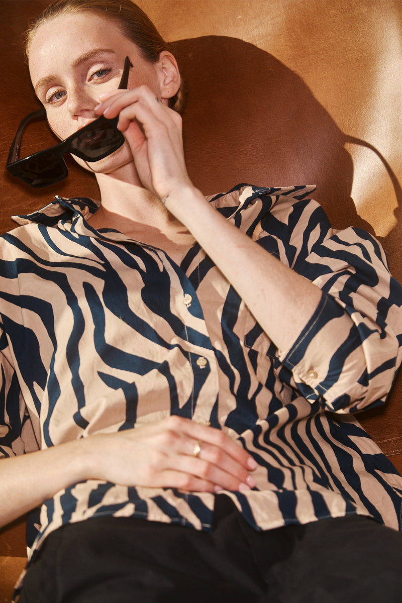 Stateside Zebra Voile Oversized Shirt in Almond-model is sitting down and holding her glasses in her face